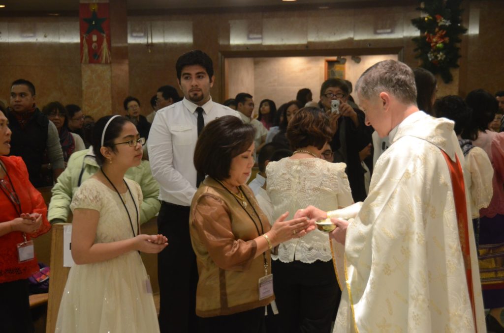 Cardinal Cupich gives communion to a parishioner of Our Lady of Mercy