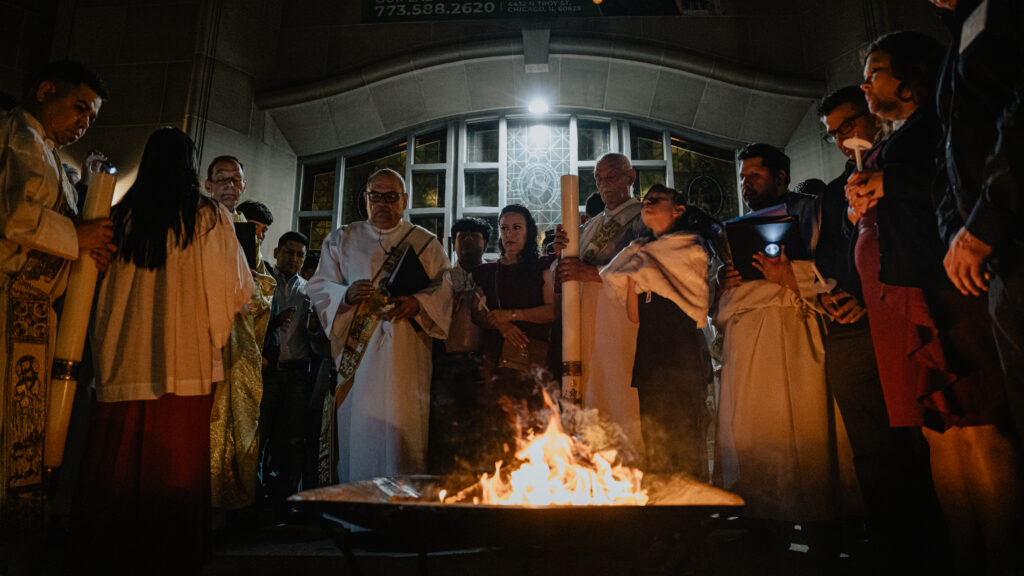 Surrounding a fire, clergy and people bless the Easter Candle