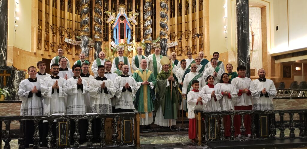 Priests, Deacons of OLM, Bishop Mark, Seminarians, Altar Servers all pose in front of the Altar.